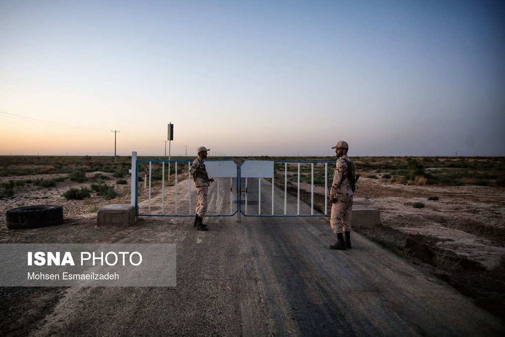 دو سرباز وظیفه در حال نگهبانی از ورودی جاده مرزی ایران در مرز تایباد هستند.