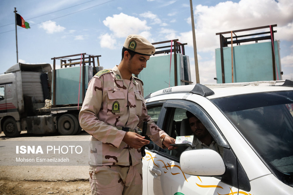 یک سرباز وظیفه مدارک شناسایی مسافران افغان را کنترل می‌کند.
