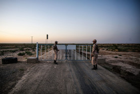 دو سرباز وظیفه در حال نگهبانی از ورودی جاده مرزی ایران در مرز تایباد هستند.