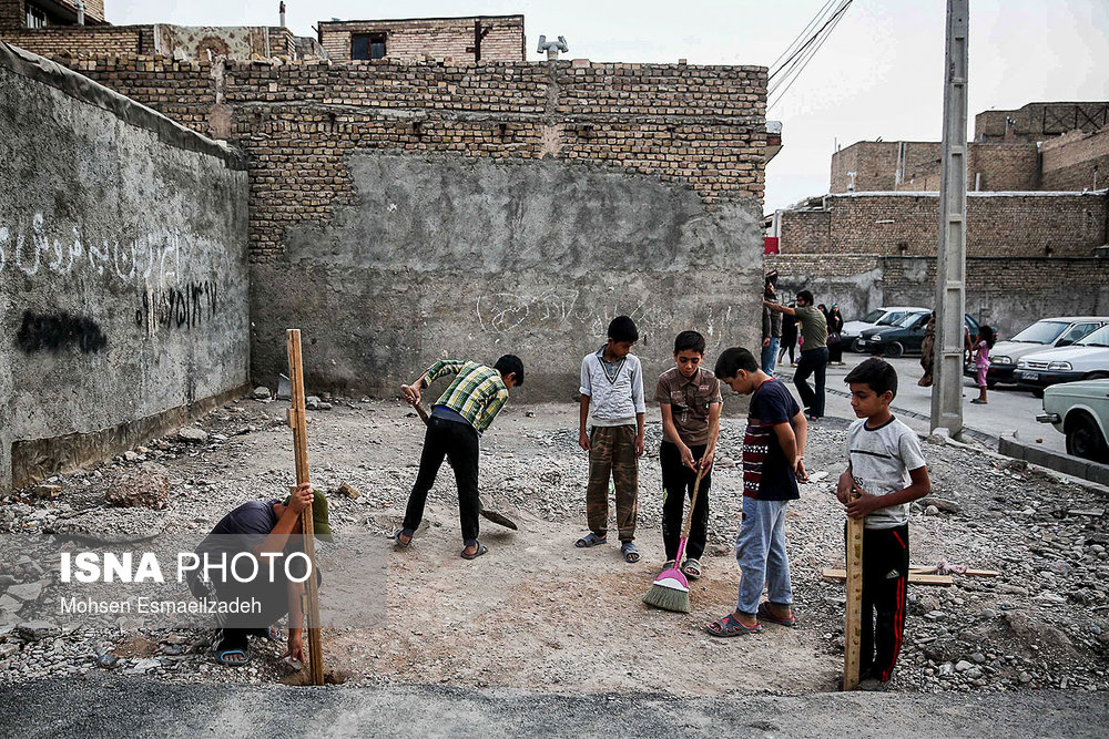 تعدادی از بچه‌های محله پورسینا مشهد، محلی را در یک زمین خالی برای برپایی موکب آماده می‌کنند.