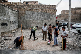 تعدادی از بچه‌های محله پورسینا مشهد، محلی را در یک زمین خالی برای برپایی موکب آماده می‌کنند.