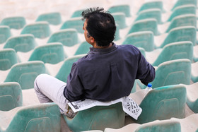 استفاده تماشاچیان از روزنامه  برای نشستن بر روی صندلی های خاکی ورزشگاه«خلیج فارس» بندرعباس