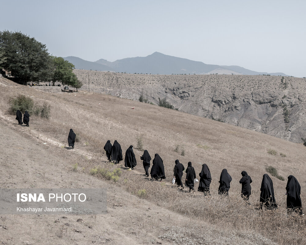 محل برگزاری مراسم در قبرستان بالای تپه‌ در اطراف روستای گنجه قرار دارد و زنان روستا برای شرکت در مراسم در حال رفتن به سمت قبرستان هستند.