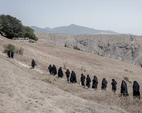 محل برگزاری مراسم در قبرستان بالای تپه‌ در اطراف روستای گنجه قرار دارد و زنان روستا برای شرکت در مراسم در حال رفتن به سمت قبرستان هستند.