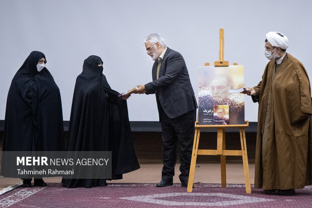 محمد مهدی تهرانچی، رییس دانشگاه آزاد اسلامی، بعد از مراسم رونمایی از کتاب" فلسفه اسلامی و فیزیک" این کتاب را به همسر شهید فخری زاده تقدیم می کند