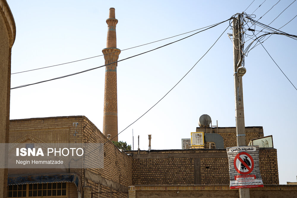 علت کج شدن "منار ساربان" را نا متقارن بودن پایه‌های این بنا بعد از ساخته شدن می‌دانند که همین باعث شده تا این مناره در حدود هشت درجه به سمت جنوب شرقی کج شود. این نشست نامتقارن احتمالا به دلیل اختلالات موجود در پی بنا یا تغییرات سفره آب زیرزمینی یا حتی استفاده از چاه‌های آب منازل اطراف اتفاق افتاده است. منازل مسکونی اطراف مناره ساربان که ساکنان آن از وجود مناره‌ها ناراضی هستند و معتقدند که عبور و مرور را برایشان دشوار کرده است.