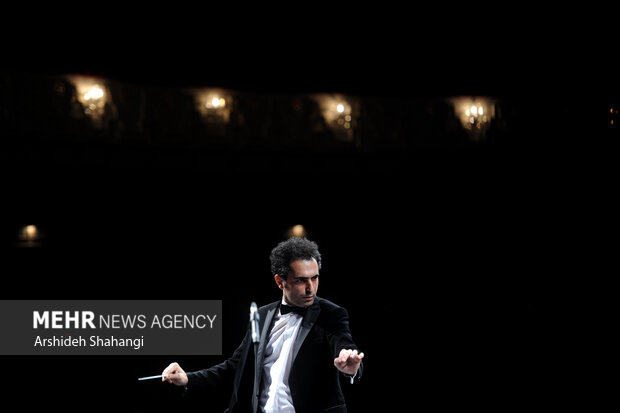 احمد مقدسی زاده رهبر ارکستر پاسوآ در حال رهبری اعضای ارکستر خود در چهارمین شب جشنواره موسیقی فجر در تالار وحدت است
