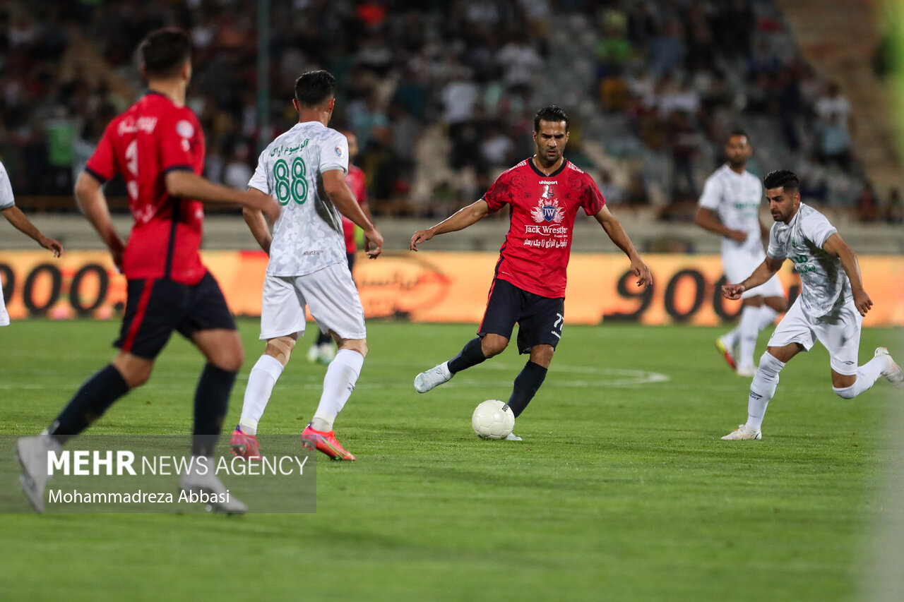 مسعود شجاعی بازیکن تیم فوتبال نساجی مازندران در حال عبور توپ از بازیکنان تیم فوتبال آلومینیوم اراک در فینال جام حذفی است