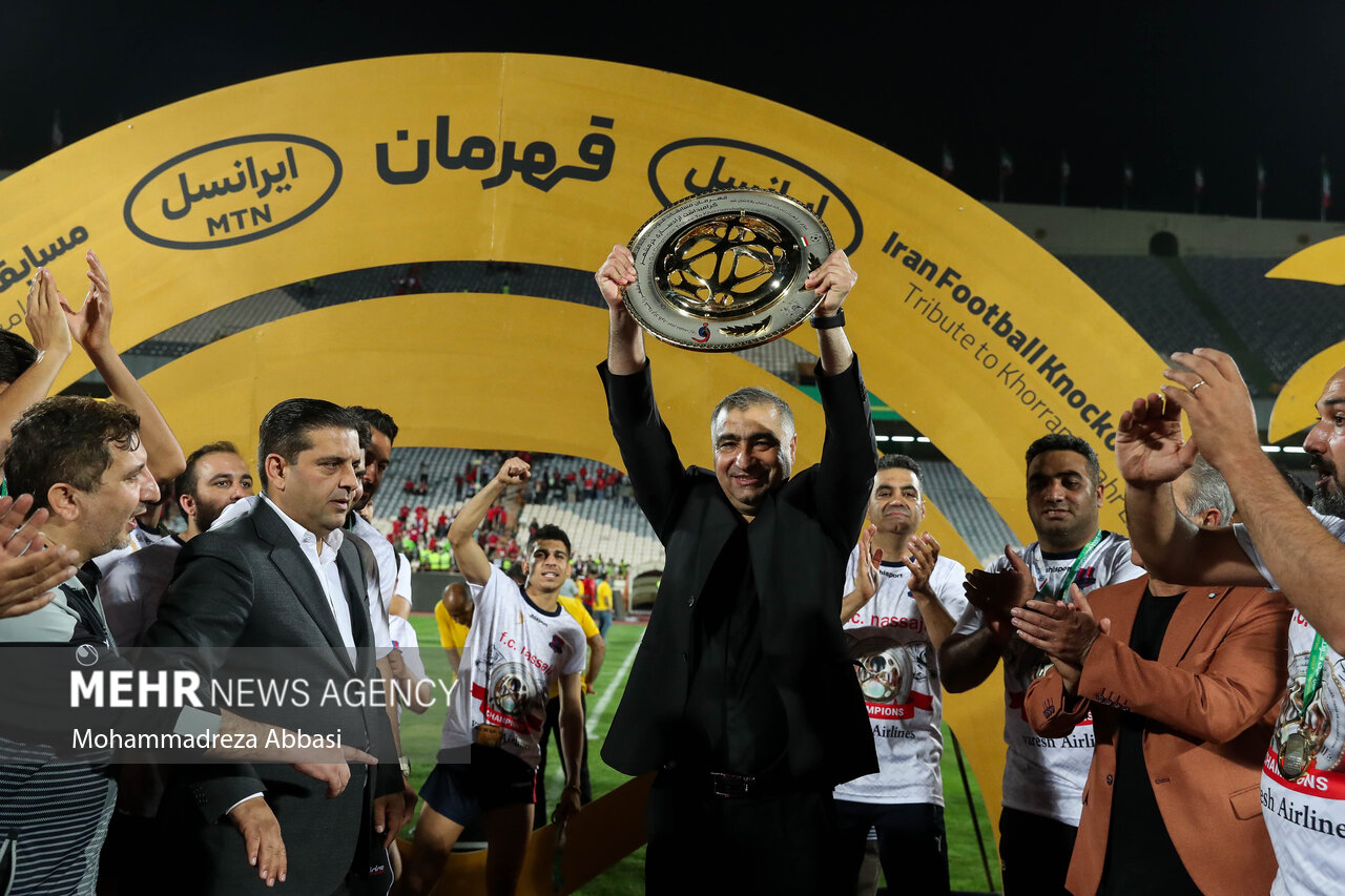 ساکت الهامی سرمربی تیم فوتبال نساجی مازنذران پس از قهرمانی تیم خود جام قهرمانی را بر روی دستان خود بلند کرده است