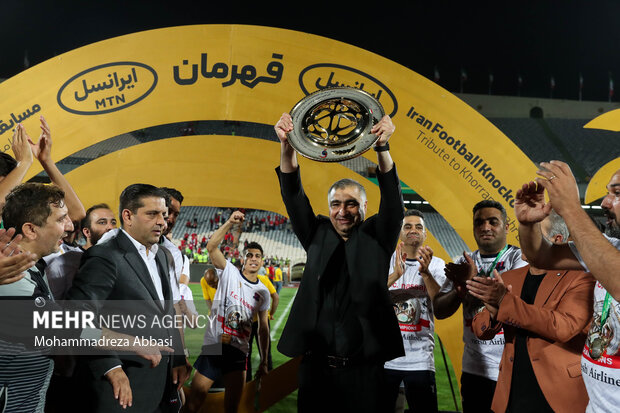 ساکت الهامی سرمربی تیم فوتبال نساجی مازنذران پس از قهرمانی تیم خود جام قهرمانی را بر روی دستان خود بلند کرده است
