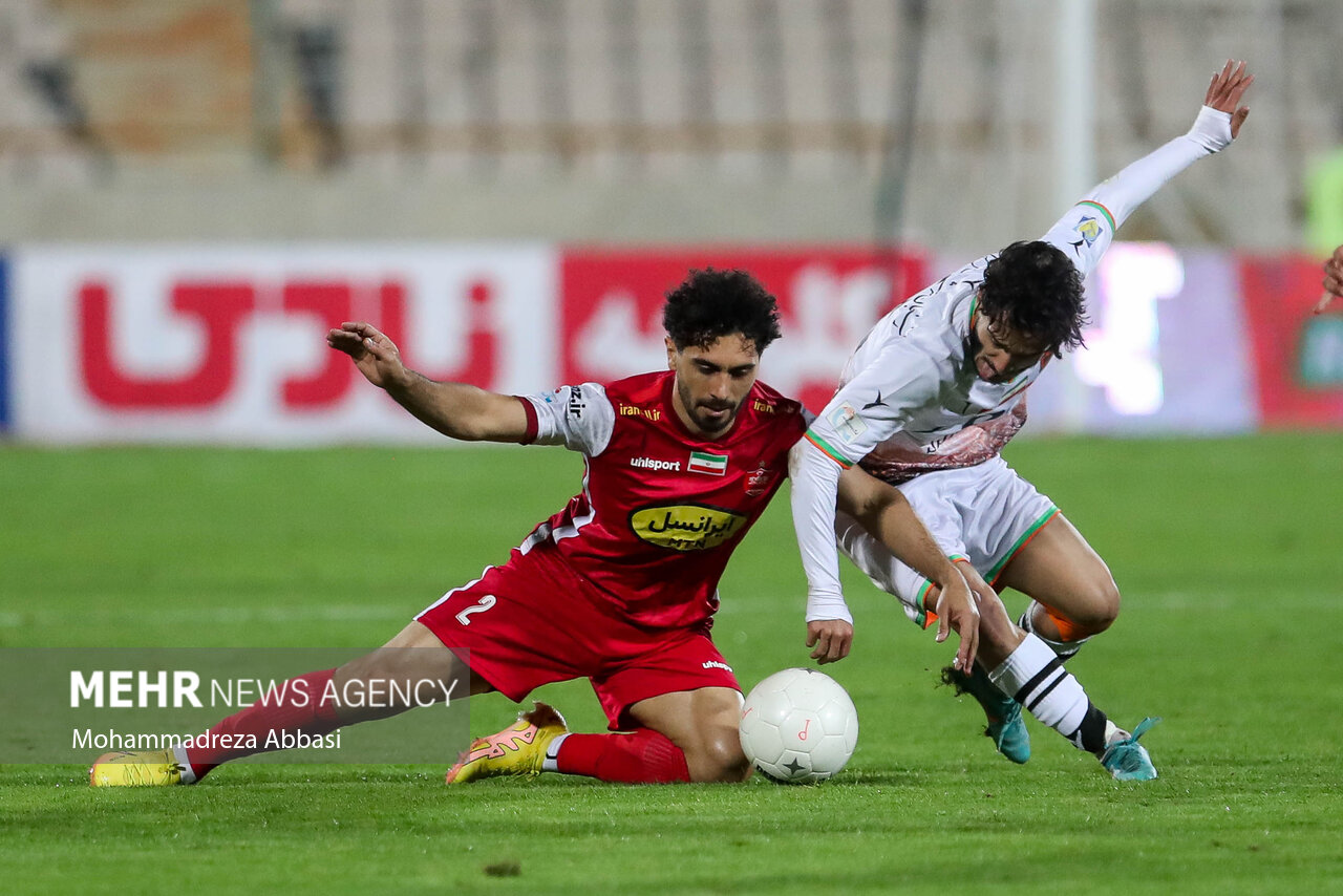 اميد عاليشاه بازيكن تيم فوتبال پرسپوليس تهران در حال عبور توپ از مدافع تيم فوتبال مس رفسنجان است