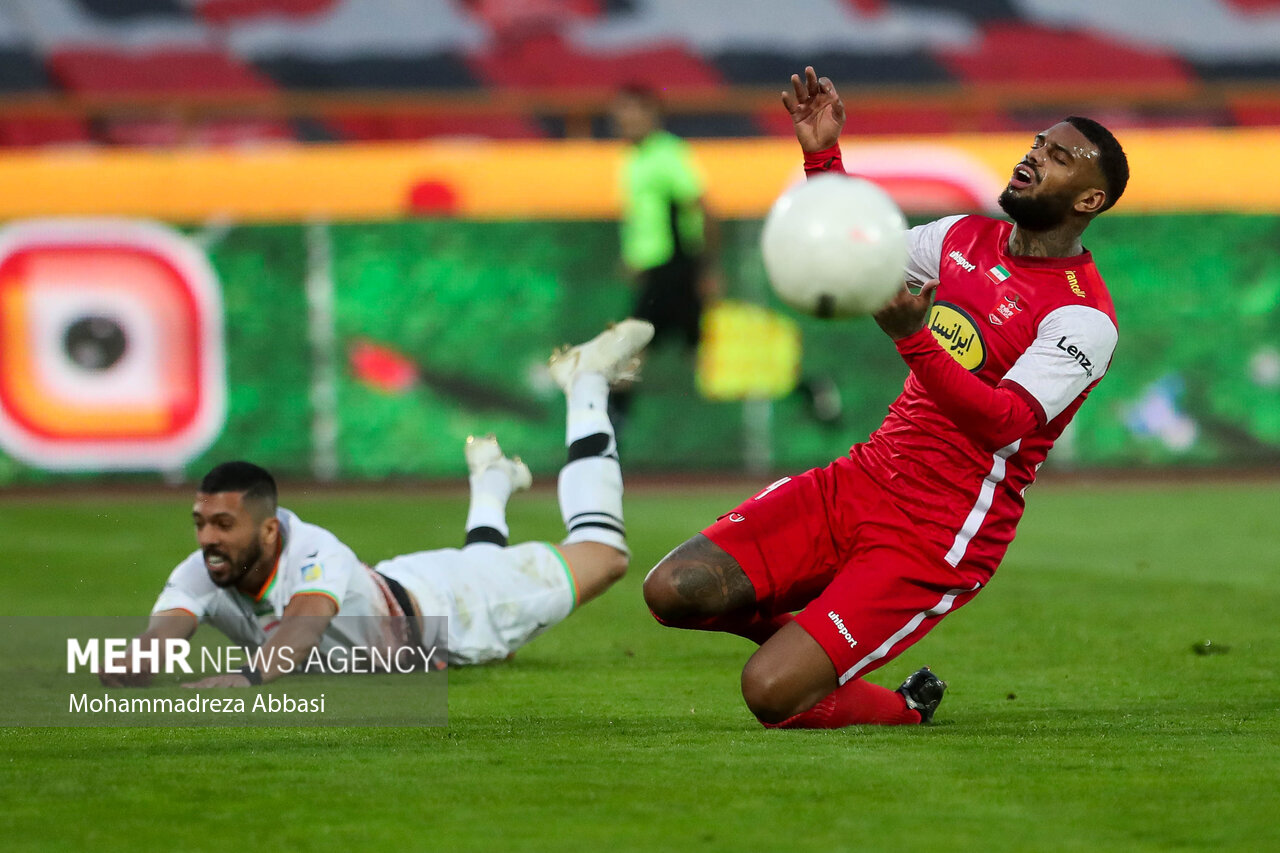 لحظه عبور توپ از مقابل جورگن لوكاديا مهاجم تیم فوتبال پرسپولیس تهران در دیدار تیم های پرسپولیس تهران و مس رفسنجان در تصویر دیده می شود