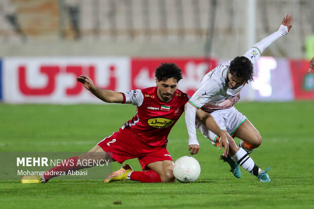 اميد عاليشاه بازيكن تيم فوتبال پرسپوليس تهران در حال عبور توپ از مدافع تيم فوتبال مس رفسنجان است