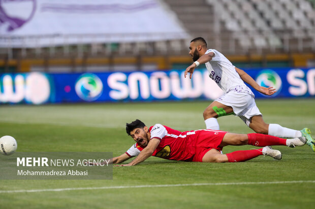 مهدی ترابی بازیکن تیم فوتبال پرسپولیس تهران در حال عبور توپ از مدافع تیم فوتبال هوادار تهران در دیدار تیم های پرسپولیس تهران و هوادار تهران است